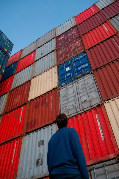 jongen kiijkkt omhoog naar op elkaar gestapelde containers